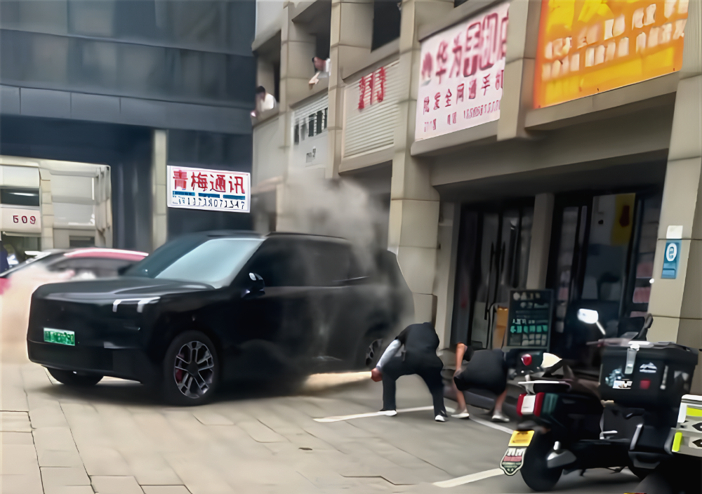 ผู้เห็นเหตุการณ์ใช้ถังดับเพลิงกับไฟที่ลุกจากใต้รถ Lynk & Co 900 ในหางโจว